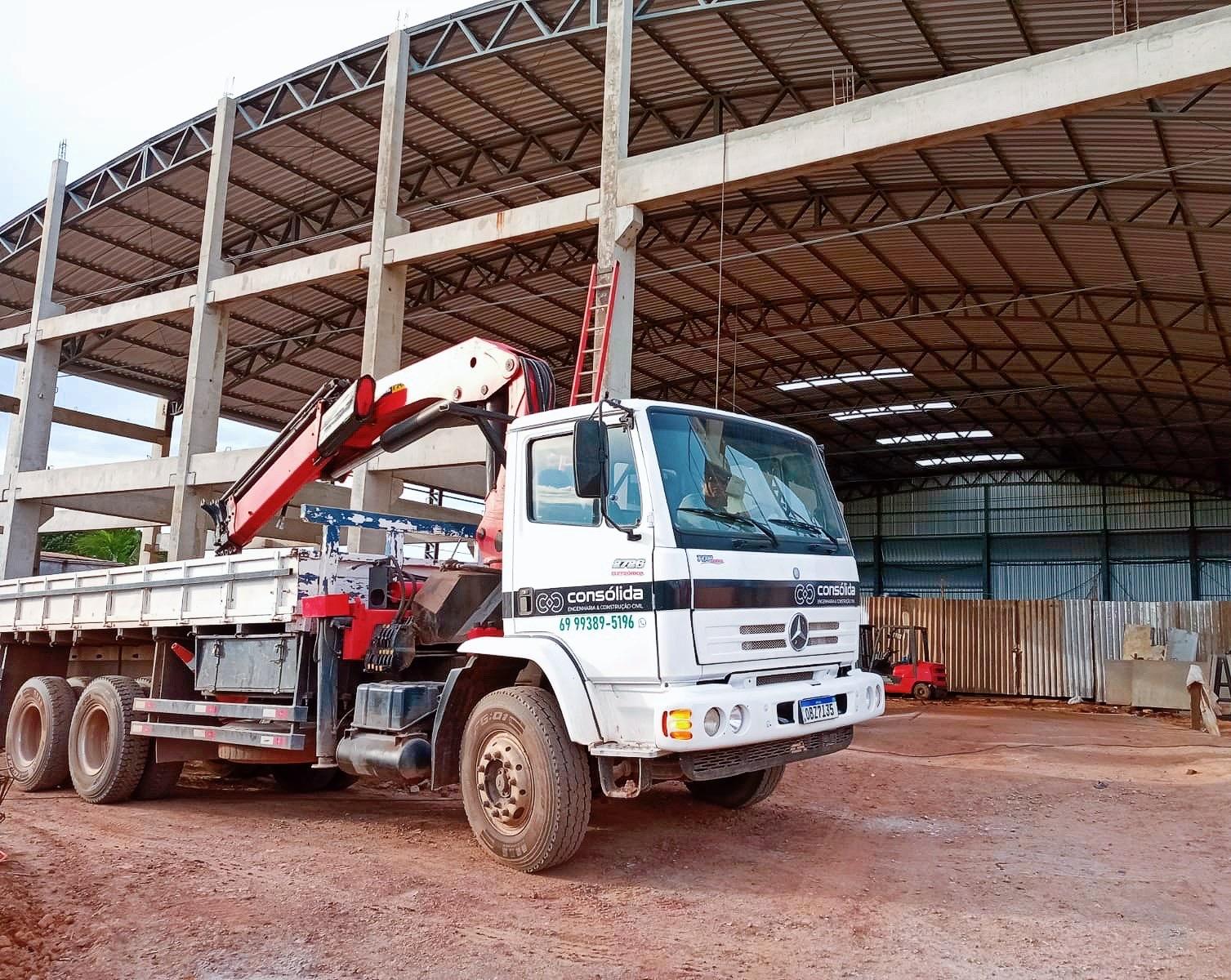 Caminhão e equipamento de içamento em uma obra estrutural